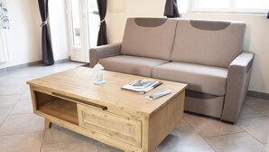 Una sala de estar con una mesa de centro de madera, un sofá y un ventanal con cortinas.