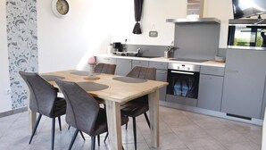 Una cocina moderna con armarios grises, un horno Bosch y un comedor con mesa de madera y sillas grises.