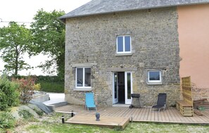 Una casa in pietra con una veranda in legno, due finestre e una porta.