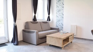 Una sala de estar moderna con un sofá gris, una mesa de centro de madera y cortinas negras.