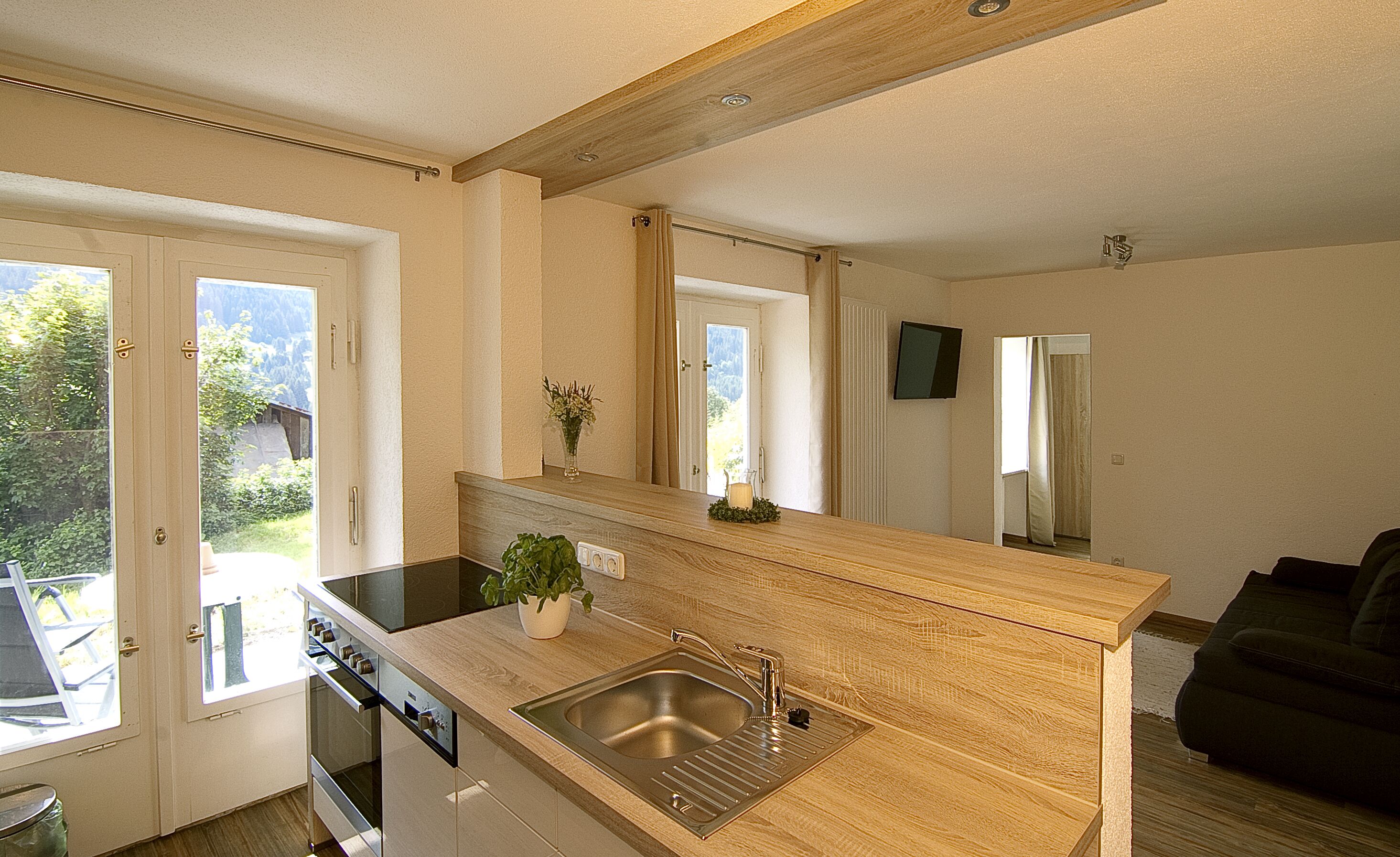 A modern kitchen with a wooden countertop, stainless steel sink, and a potted plant.