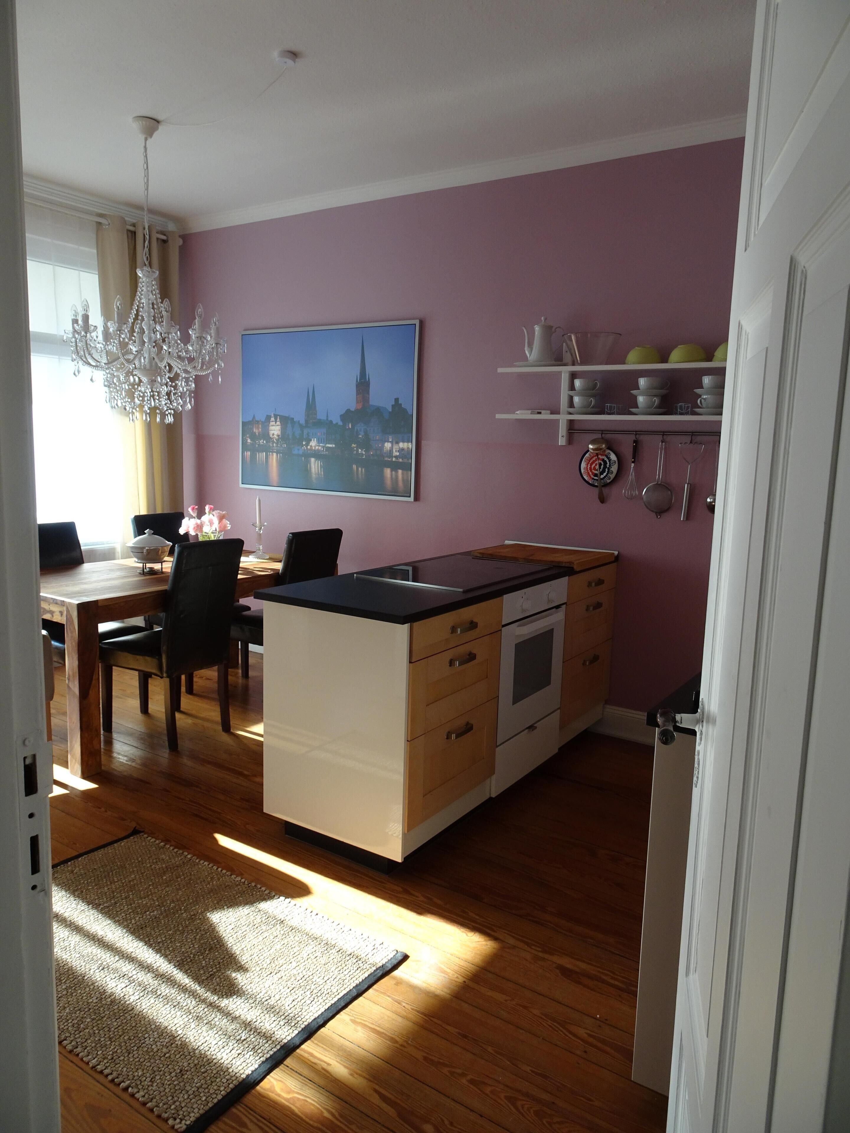 Una cucina moderna con mobili in legno, un'area pranzo con un lampadario e un quadro raffigurante un panorama urbano.