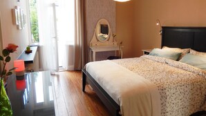 A bedroom with a bed, bedside table, mirror, and a window with curtains.