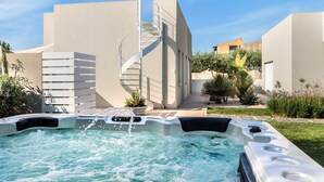 Ett bubbelbad i en innergård med en spiraltrappa och en pool.