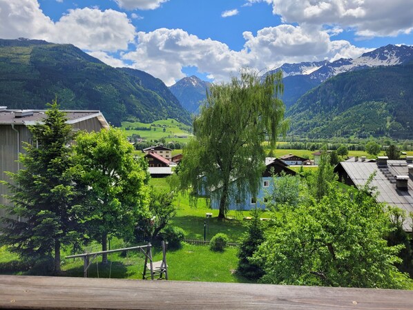 A rural village with houses, a wooden bridge, and mountains in the background.