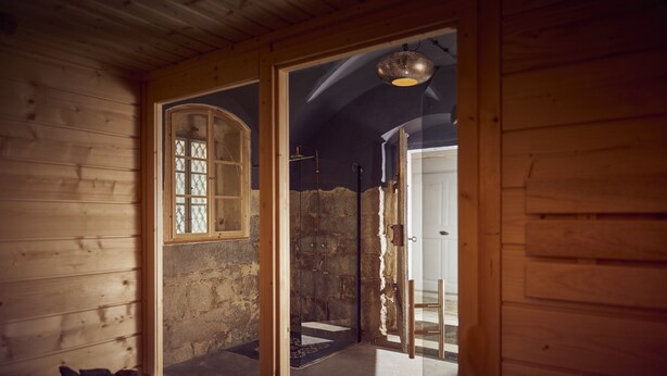 A wooden cabin interior with a stone wall, a wooden bench, and a door leading to a stone staircase. - Large, lovingly renovated half-timbered house with sauna & garden (Ebersbach-Neugersdorf)