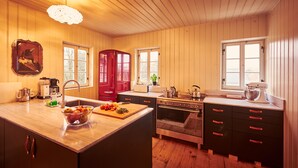 A kitchen with wooden cabinets, a red refrigerator, a sink, and a large island with a fruit bowl. - Large, lovingly renovated half-timbered house with sauna & garden (Ebersbach-Neugersdorf)