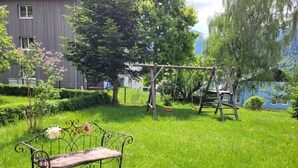 Un espace herbeux avec un banc en bois et une balançoire.
