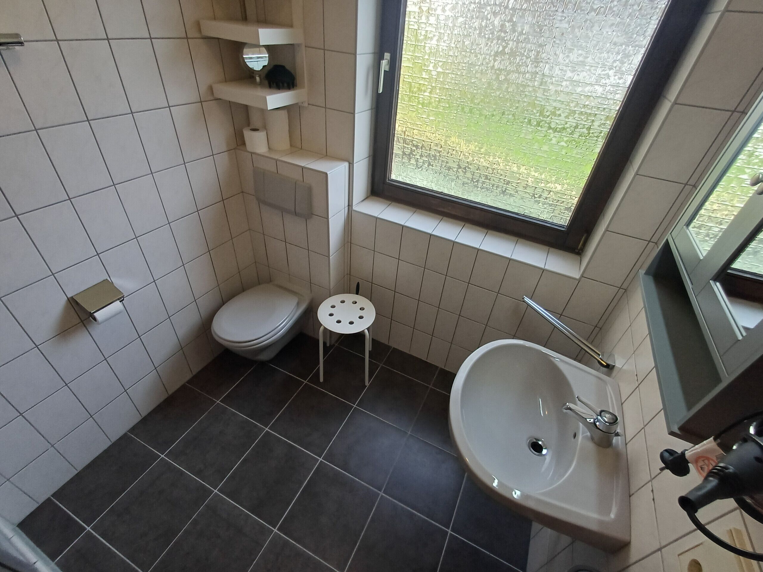A small bathroom with a toilet, a sink, and a window.