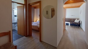 Un couloir mène à une chambre à coucher qui contient un lit, un miroir rond et un canapé dans un coin salon.