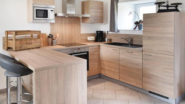 Una cocina moderna con armarios de madera, un microondas integrado, una cafetera y un lavamanos.