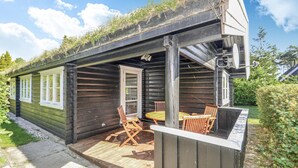 A log cabin with a porch, wooden chairs, and a table. - 3 bedroom gorgeous home in Gedser (Gedser)