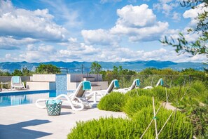 A pool area with lounge chairs and a view of mountains.