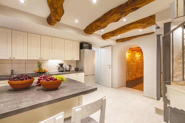 A modern kitchen with white cabinets, a granite countertop, and a fruit bowl.