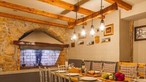 Un'accogliente zona pranzo con parete in pietra, travi in legno e camino in mattoni.