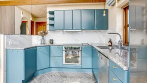 A modern kitchen with blue cabinets, a marble countertop, and a built-in oven.
