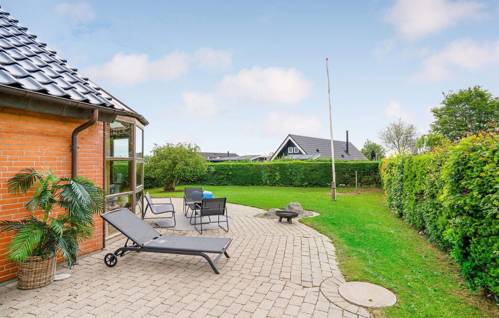 Een terras met lounge fauteuils, een kleine tafel en een vuurkorf.