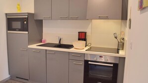 A compact kitchen with grey cabinets, a Bosch microwave, a coffee maker, and an oven.