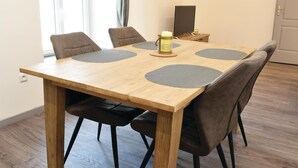 A wooden dining table with four grey placemats, surrounded by six brown chairs.