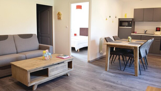 A modern apartment with a living room, dining area, and kitchen.