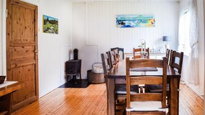 Un coin repas avec une table et des chaises en bois, un poêle et deux tableaux accrochés au mur.