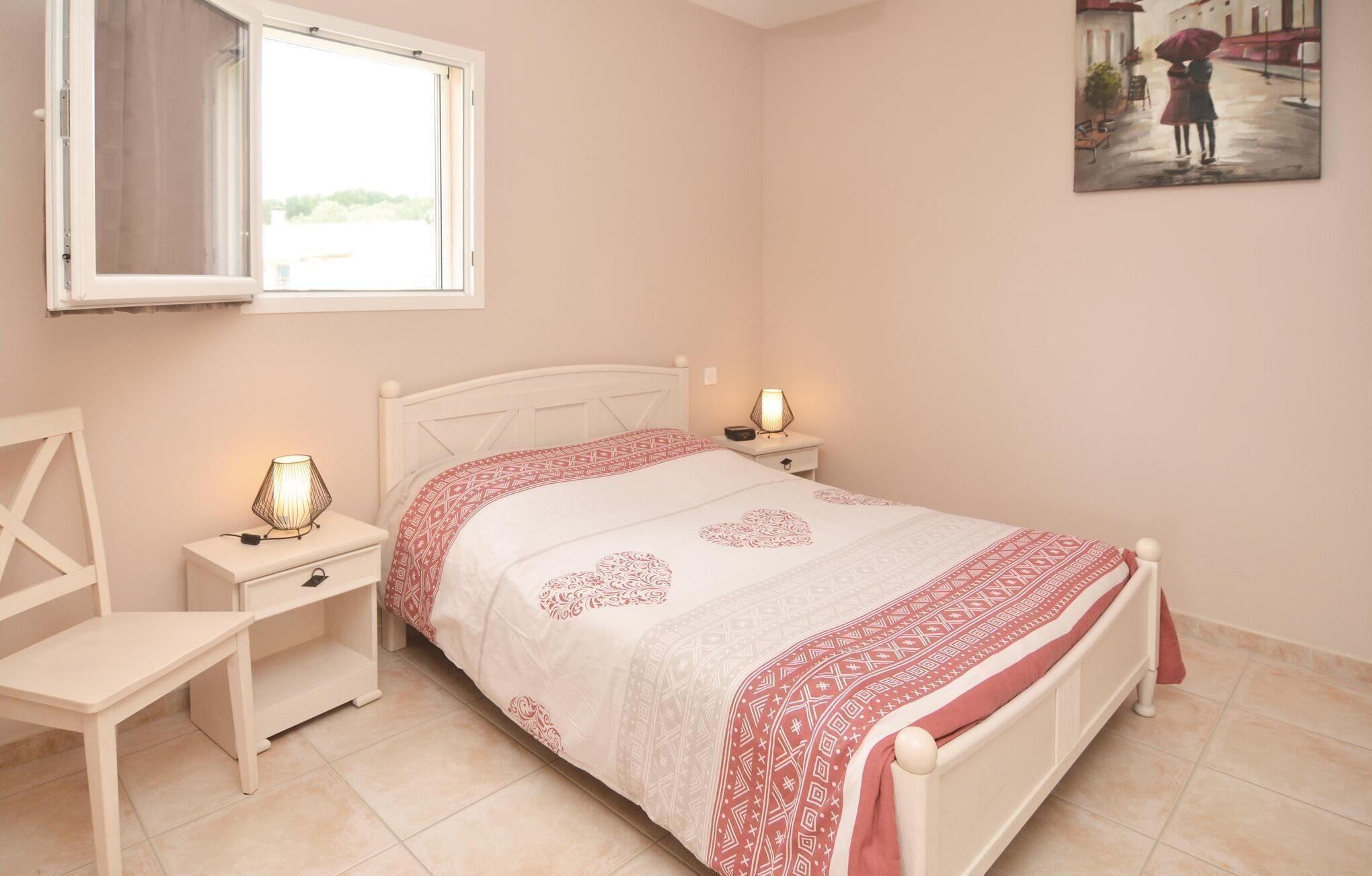 Une chambre à coucher avec un lit, des tables de chevet, une chaise, une fenêtre et un tableau au mur.