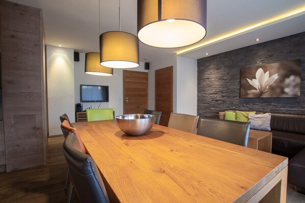 A modern dining area with a wooden table, metal bowl, and leather chairs.