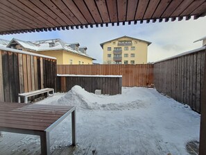 A covered outdoor area with a wooden bench and a snow-covered ground.