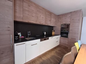 A modern kitchen with wooden cabinets, a black countertop, a sink, and a built-in oven.