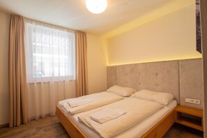A double bed with a wooden frame, two pillows, and a bedside table with a lamp.