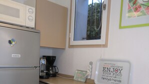 A compact kitchenette with a refrigerator, a coffee maker, and a window above the sink.