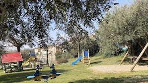 Une aire de jeux avec un toboggan, des balançoires et une structure d’escalade.
