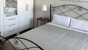 Une chambre à coucher comprenant un lit, une armoire, une table de chevet, une lampe et un élément décoratif mural.