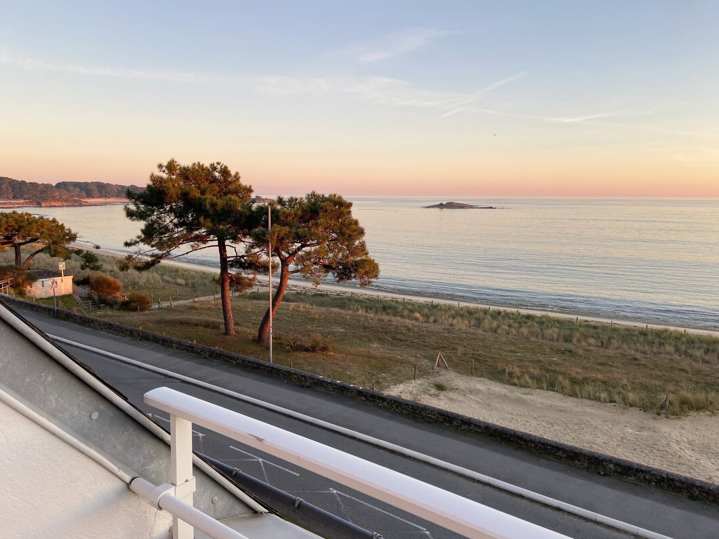A coastal road with a view of the sea and a small island in the distance.