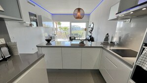 A modern kitchen with white cabinetry, a central island, and a view to the outside. - 9 - Apartment in Reserva de higueron , Benalmadena (Benalmádena)