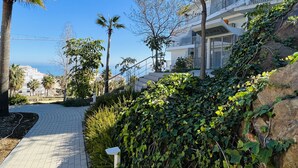 A paved pathway leading to a modern building with a balcony, surrounded by greenery and palm trees. - 9 - Apartment in Reserva de higueron , Benalmadena (Benalmádena)