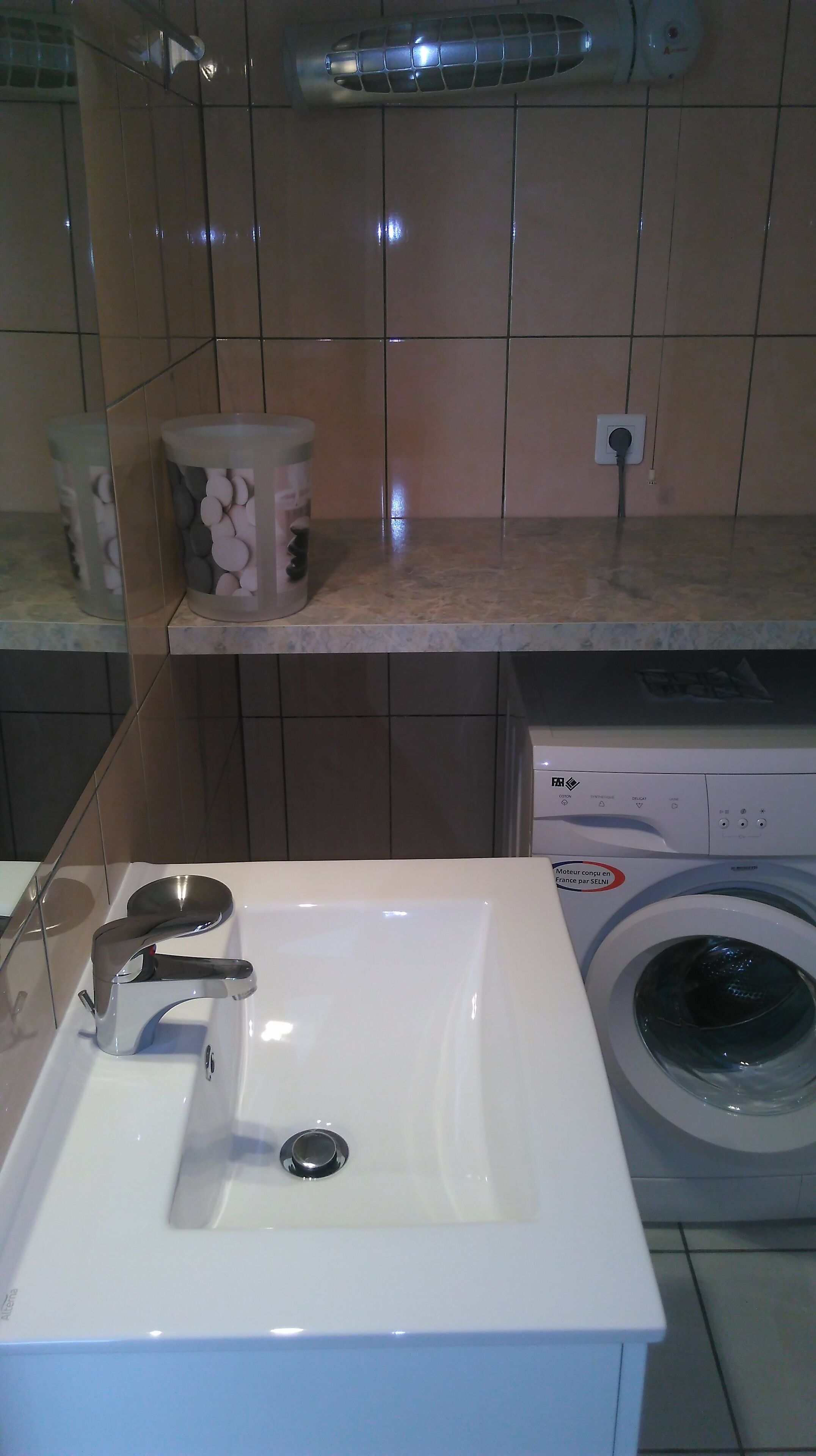 A bathroom with a white sink, a washing machine, and a towel rack.