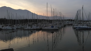 A marina with numerous sailboats docked, a mountain in the background, and calm water reflecting the boats. - Santa Lucia, Unit 357 (Santa-Lucia-Di-Moriani)
