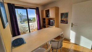 A small kitchenette with a counter, two stools, a TV, and a poster on the wall. - Beautiful appartment with sea view and near of the beach (SIX FOURS LES PLAGES)