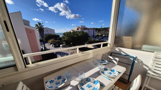 A balcony with a table set for two, overlooking a residential area with buildings and trees. - Beautiful appartment with sea view and near of the beach (SIX FOURS LES PLAGES)