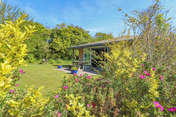 A garden with a patio area, a lawn, and a building with a sloped roof.