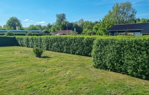 A well-maintained grassy area with neatly trimmed hedges and a clear sky.