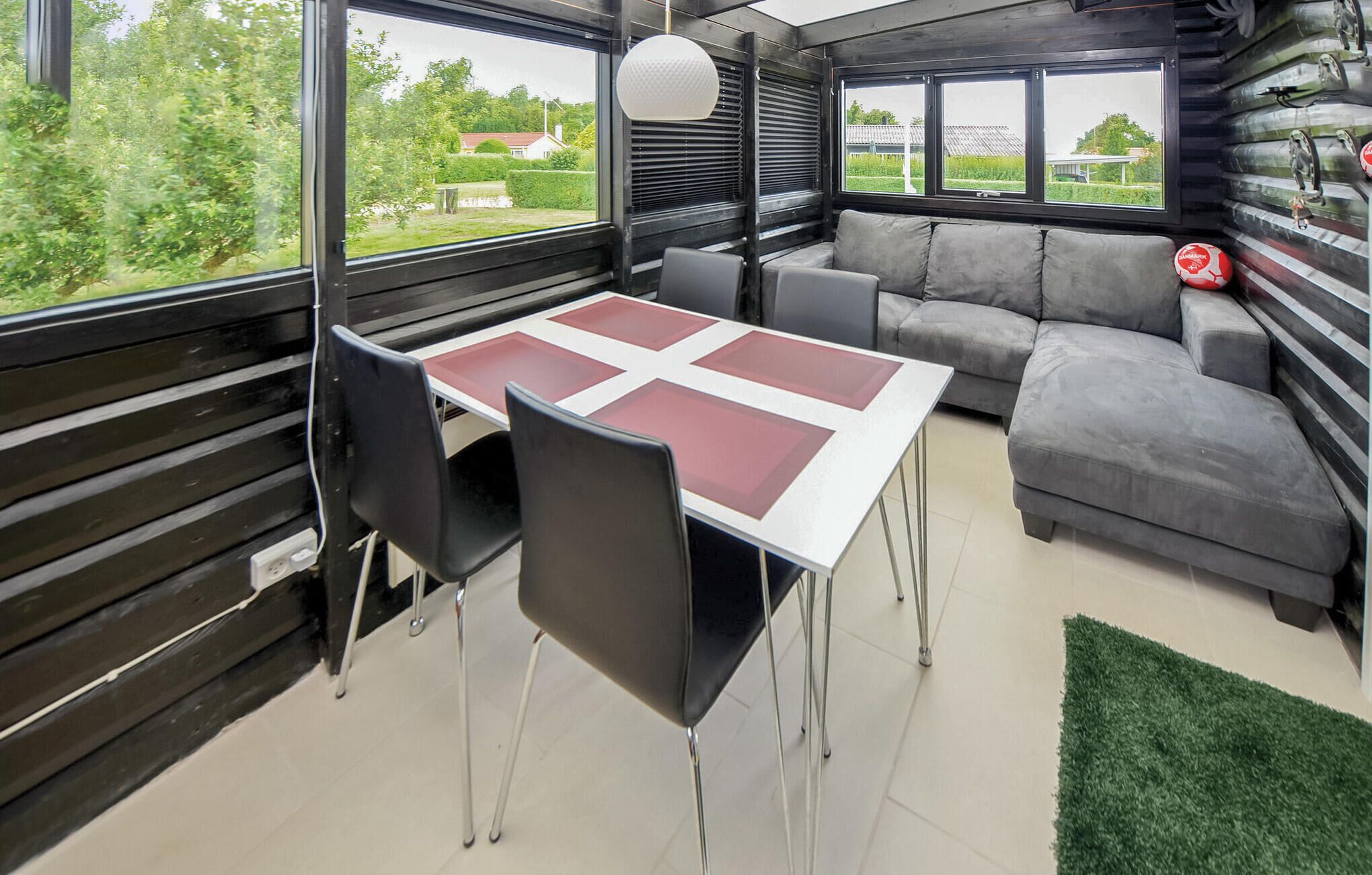 Een modern interieur met een eettafel, stoelen, een bank en grote ramen met uitzicht op groen en huizen.
