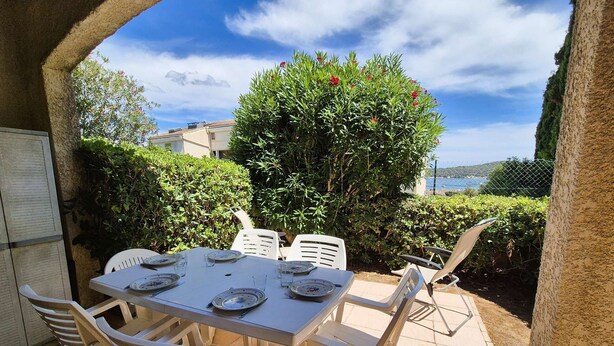 An outdoor patio with a table set for four, surrounded by white plastic chairs, under a clear sky. - Garden with barbecue, swimming pool (LA SEYNE SUR MER)