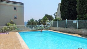 A swimming pool with a metal fence and a person swimming. - Garden with barbecue, swimming pool (LA SEYNE SUR MER)