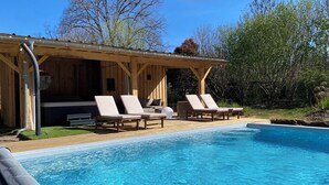 A wooden cabin with a pool and lounge chairs. - Charming bergerie *** gîte & spa (Pouydesseaux)