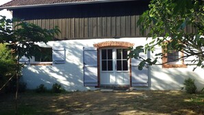 A house with a brick facade, white shutters, and a small front porch. - Charming bergerie *** gîte & spa (Pouydesseaux)
