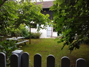 A backyard with a picnic table, a small tree, and a fence. - Charming bergerie *** gîte & spa (Pouydesseaux)