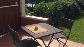 An outdoor patio with a table and two chairs, surrounded by greenery and a view of a lake and hills. - T2 1 bedroom 4 people for rent 83700 Saint Raphaël / Le Dramont  (Saint-Raphaël)