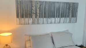 A bedroom with a bed, a bedside table with a lamp, a wall-mounted artwork, and a nightstand. - Perfect Location / Perfectly Located Ski-in / Ski-out  (Mont-Tremblant)